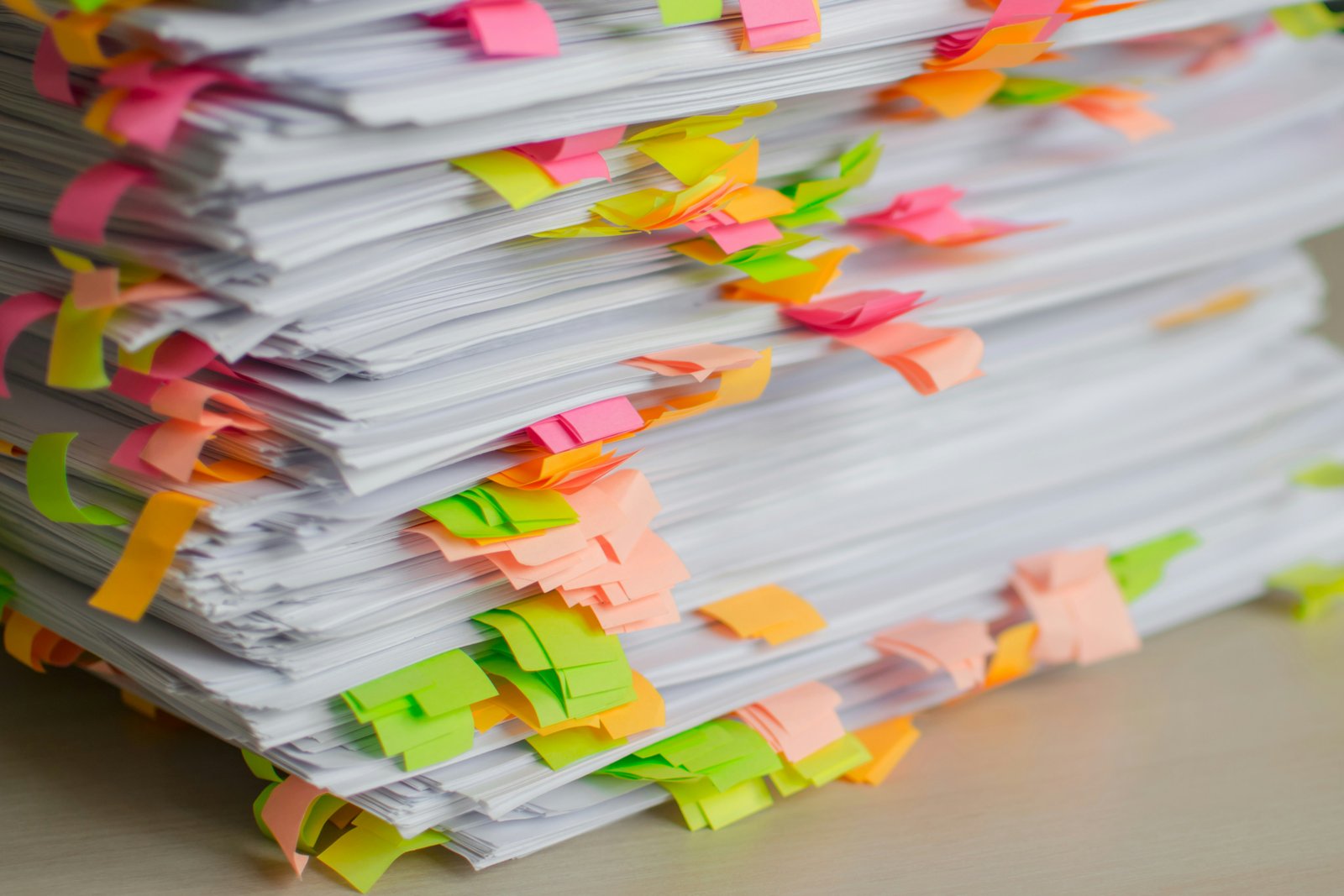 Stack of distributor purchase invoices and paperwork tagged with colour-coded notes